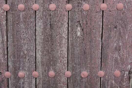 Weathered wooden door texture with rows of round iron studs
