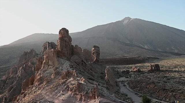 The Roque Cinchado rock formation sits beneath the bare slopes of Mount Teide under a clear midday sky. A landmark shot of Spain's highest peak inside its UNESCO listed national park on Tenerife.