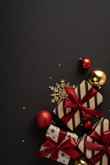 Obraz premium Merry Christmas and happy New Year gifts with red ribbons gold ornaments on vertical dark black background with space for design