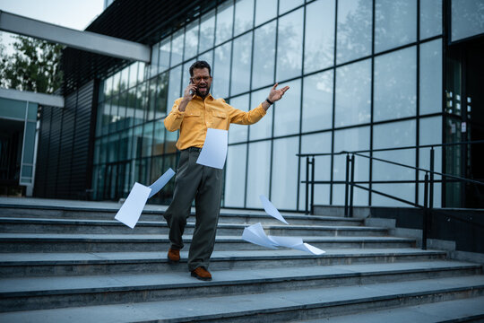 Stressed businessman receiving bad news, papers falling