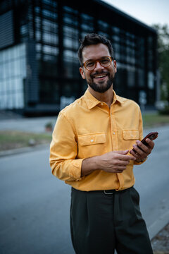 Man smiling using smartphone in urban setting
