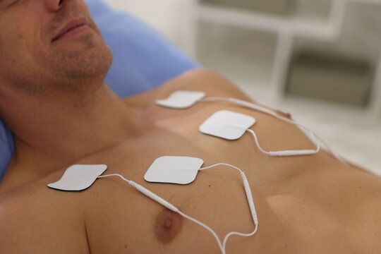 Patient with ECG electrodes attached to his chest in clinic, closeup