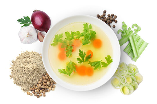 Broth in bowl, celery stalks, onions, garlic and peppercorns on white background, top view