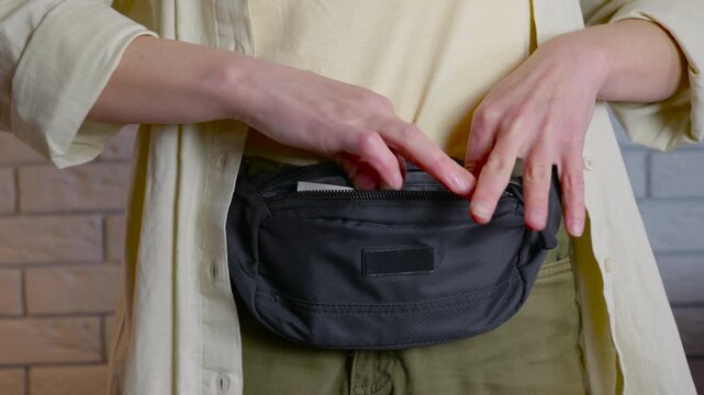 Woman counting various currencies from a fanny pack. Female hands opening a fanny pack to take out various international currency bills, including us dollars, turkish lira, then putting the money back