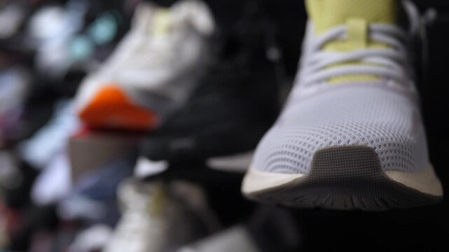 Running shoe advances on treadmill belt during workout. White mesh sneaker with orange tip stays centered as fitness motion repeats, creating concentrated athletic mood and energetic rhythm.