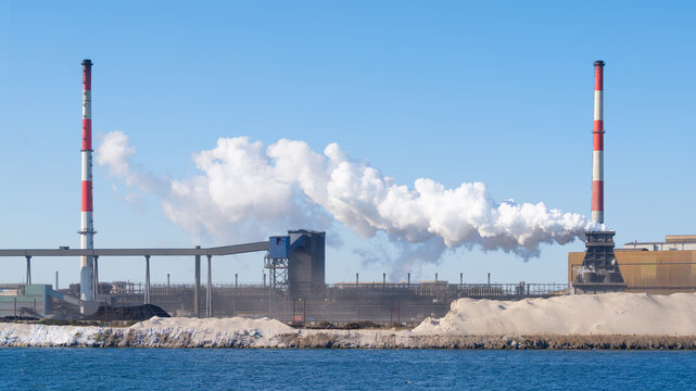 Heavy industrial steel plant with smoke emissions into the atmosphere. Metallurgical manufacturing process and environmental air pollution.