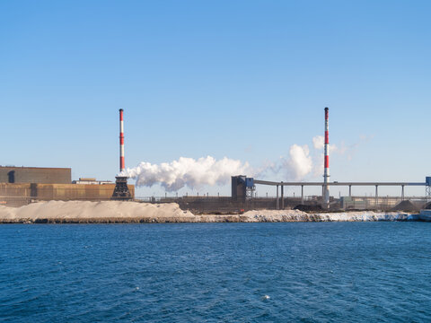 Heavy industrial steel plant with smoke emissions into the atmosphere. Metallurgical manufacturing process and environmental air pollution.