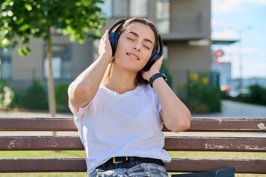 Young woman enjoying music in headphones with eyes closed outdoors