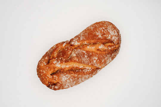 Crusty whole rustic loaf with flour dusting and scored golden crust on clean white background closeup texture for bakery packaging
