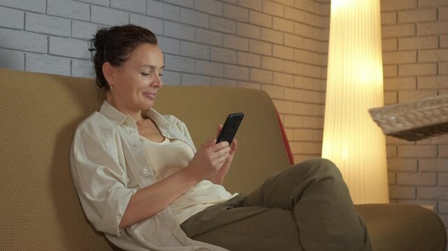 Negative impact of technology on relationships. Woman sitting on a sofa and happily scrolling through her smartphone becomes angry when a man asks her to put it away