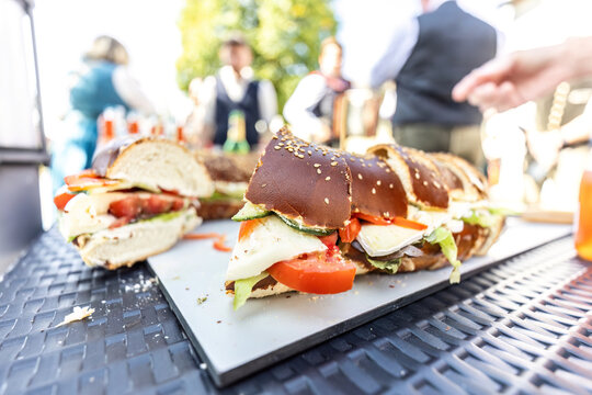 Bavarian pretzel sandwiches with cheese, tomato, cucumber and lettuce served outdoors at a traditional folk festival.