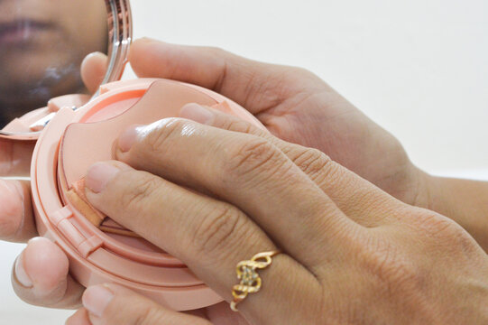 Female hands applying makeup with beauty sponge applicator puff,