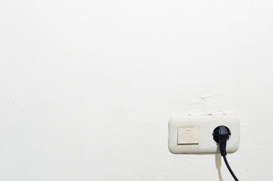 Black plug plugged into outlet on white wall