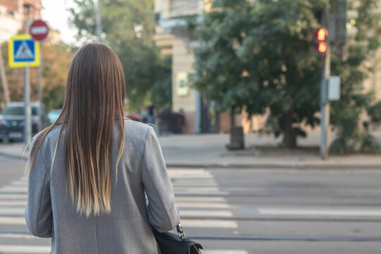 A young woman is currently waiting for the green light to cross the road.