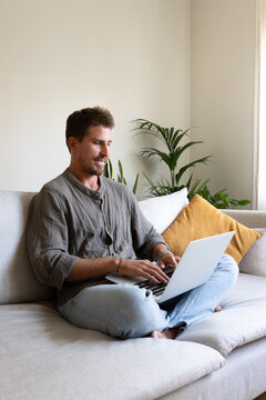 Freelancer working from home sitting on sofa using laptop