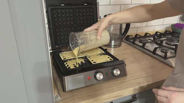 Filling waffle iron evenly with batter before cooking Close kitchen scene perfect for baking tutorials breakfast recipes and food blog content