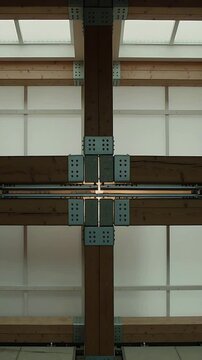 Vertical video: Sliding white T fixture shifting along rail at timber beam joint, showing seam glow