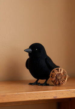 Tiny felt raven beside a dried seed head