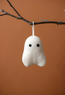 Ivory felt ghost hanging from a bare branch