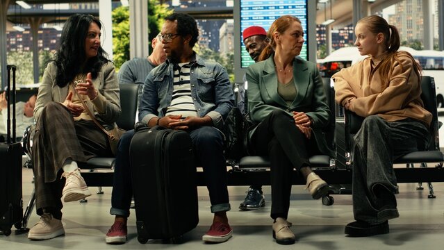 Diverse travelers wait in a busy metropolitan bus station while passengers fill the hall and public transportation keeps the terminal in constant motion.
