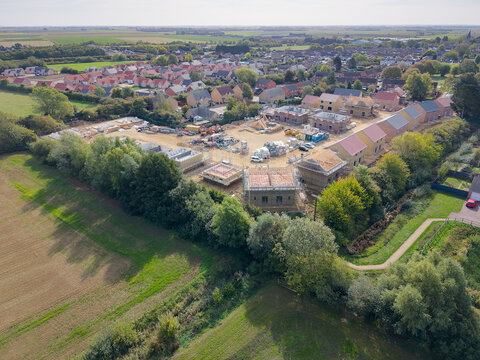Interesting drone UAV view of a corner plot of a British housing estate accommodating both affordable and private homes. The corner plot shows the roofing timber frames.