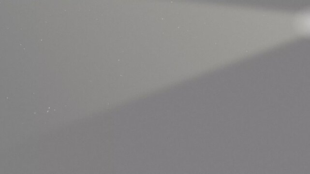 Textured analog film grain overlay showing soft diagonal gradient across neutral grey surface