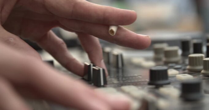 Sound technician hands operating analog audio mixer at live event