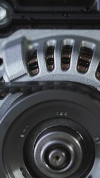 Vertical video: Spinning rotor being powered, turning in engine bay, droplets shifting on flange