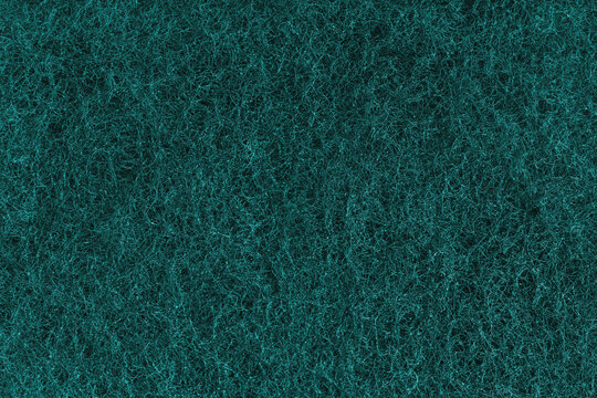Abstract turquoise felt texture with dense fibers, fluffy structure of carpeting or artificial grass close up, macro. Textile surface, material for sports flooring, backgrounds, upholstery and design