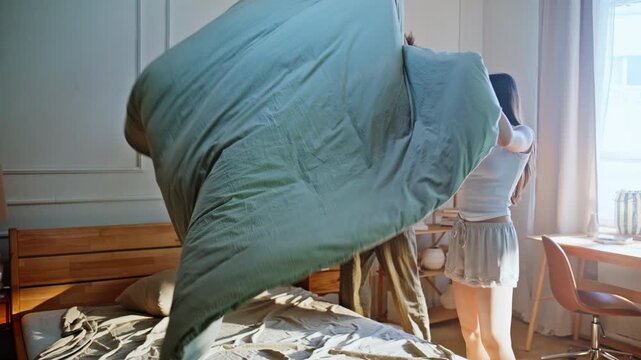 Partners making bed together morning. Interracial pair changing bedding home.
