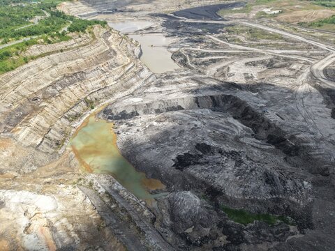 An aerial view of a coal mine featuring a very deep excavation and various mining activities