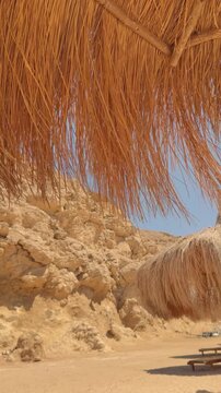 Scenic desert landscape with straw umbrellas and rocky cliffs