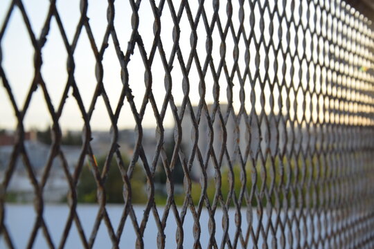 Diamond wire mesh fence with blurred urban background