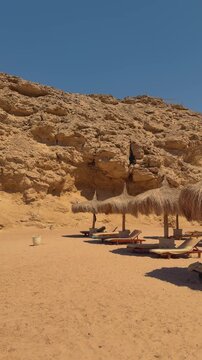 Serene desert oasis beach with rustic sun umbrellas and lounge chairs