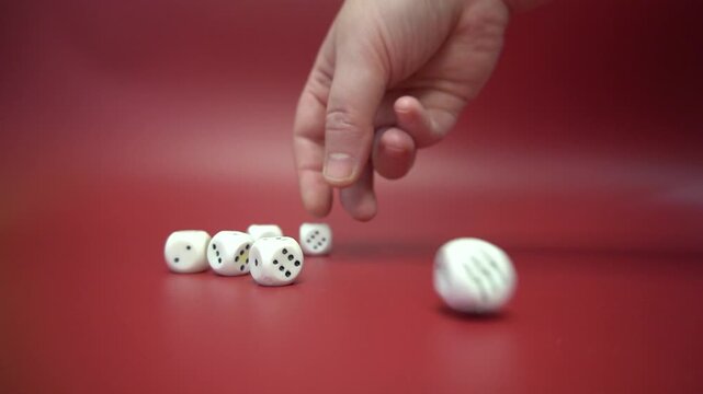 The hand rolls dice on a red background. White cubes, motion and blur, studio production, close-up.