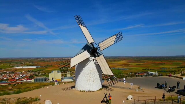 Single white windmill against a blue sky with people in the foreground and a vast landscape in the background, aerial view, Consuegra, Toledo, Castilla-La Mancha, Spain