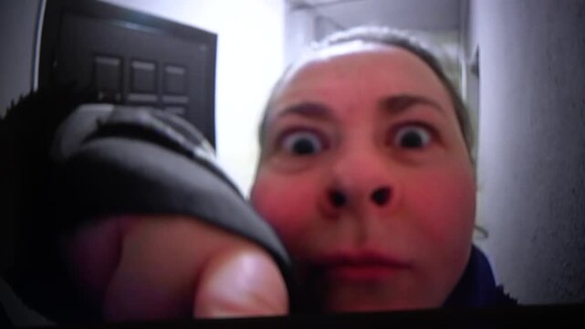  A woman knocks on the door next to the peephole in close-up.