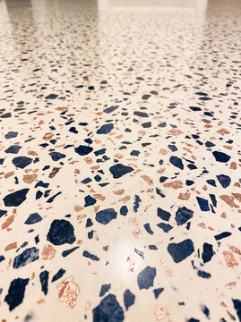 Close-up terrazzo surface featuring colorful stone chips embedded in a light cream base. The contemporary material creates a refined geometric texture suitable for interiors, architecture, flooring, a
