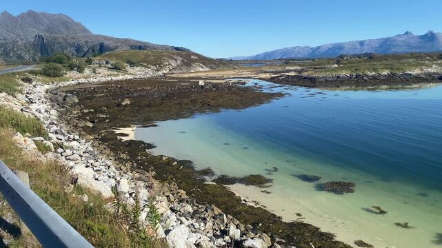 Picturesque coastline with clear waters and mountains in the background under a blue sky, Her&ouml;y, Seven Sisters, FV 17, RV 17, Kystriksveien, Nordland, Norway