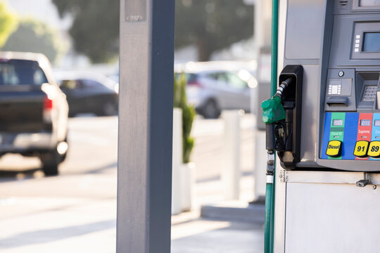 A Diesel pump and hose hangs at a gasoline station.