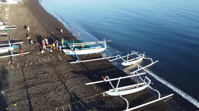 Fishermen return in the morning with their outrigger boats to the black beach of Amed, with Mount Agung in the background, Amed Bali, Indonesia