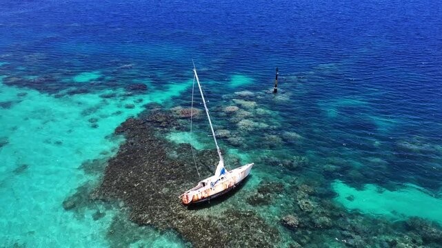 4k aerial video footage - flying around partly rosty grounded Single-Masted Sailboat in the Turquoise Lagoon of shore  Bora Bora, French Polynesia