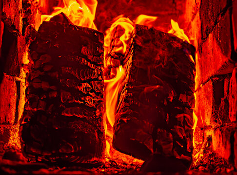 Close up of burning logs in a rustic fireplace with bright orange flames