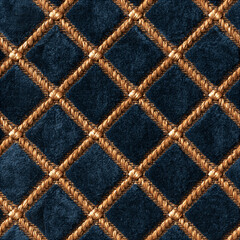 Fototapeta premium Seamless pattern blue velvet fabric forming a diamond quilted pattern, separated by golden braided ropes. Representing luxury, elegance, and rich texture