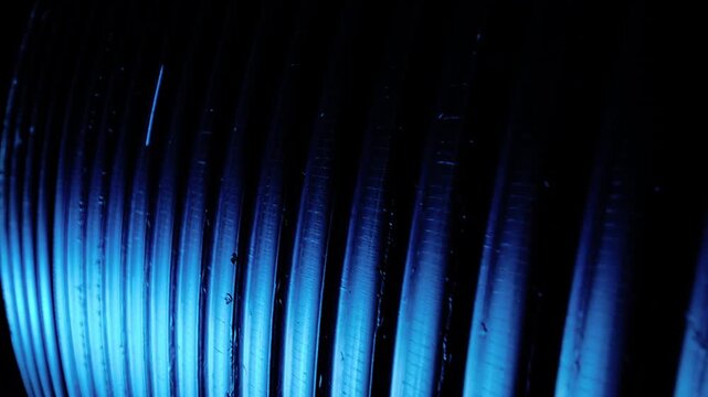 Close-up motion scene of tightly spaced parallel cylindrical ridges running diagonally from lower-left to upper-right under directional cool blue lighting, with abstract, closeup, macro, ridge detail