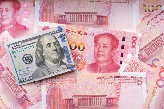 Single US dollar banknote over scattered Chinese yuan notes shows currency contrast, exchange rates, US-China trade tensions, and global finance for editorial use. Real Photo