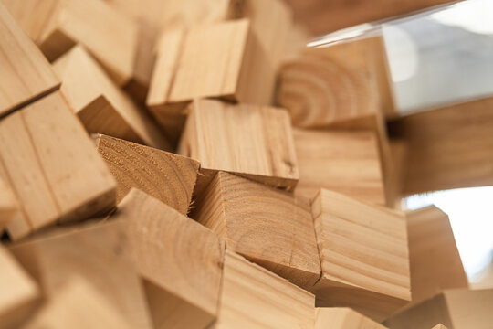 Pile of small cut pine wood blocks in warm natural tones from pallet production at a sawmill, sustainable natural raw material for construction as part of a smart factory research project