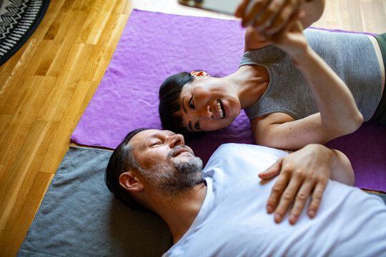 Couple taking a selfie while resting on yoga mats at home