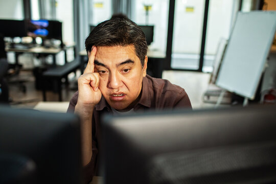 Frustrated office worker staring at computer screens