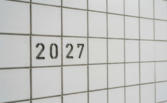 Minimalist white tiled wall with the number 2027 stencil design representing future concepts and planning